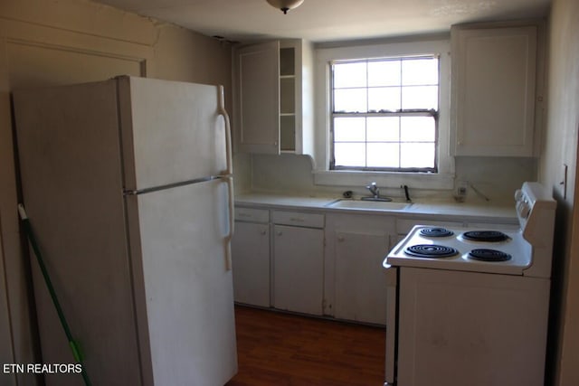 kitchen with white appliances, white cabinets, wood finished floors, light countertops, and a sink