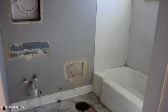 bathroom featuring a tub to relax in and baseboards