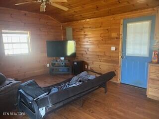 living room featuring lofted ceiling, a ceiling fan, wood ceiling, wood walls, and wood finished floors