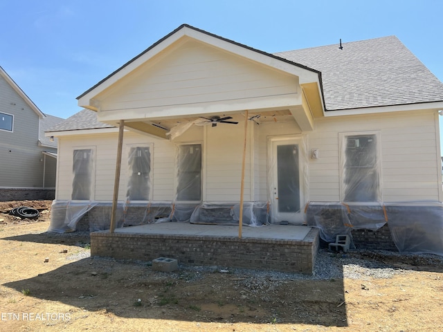 view of front facade with a patio, ceiling fan, and roof with shingles