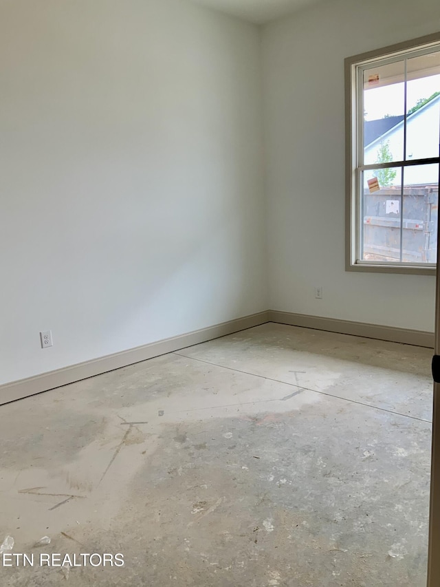 empty room featuring concrete floors and baseboards