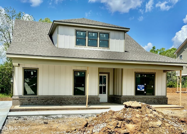 view of front facade with board and batten siding, a porch, and a shingled roof