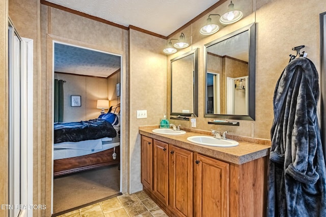 ensuite bathroom featuring a textured ceiling, ornamental molding, a sink, and ensuite bathroom