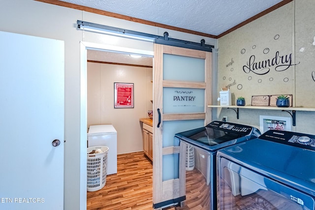 kitchen featuring a barn door, ornamental molding, wood finished floors, a textured ceiling, and separate washer and dryer