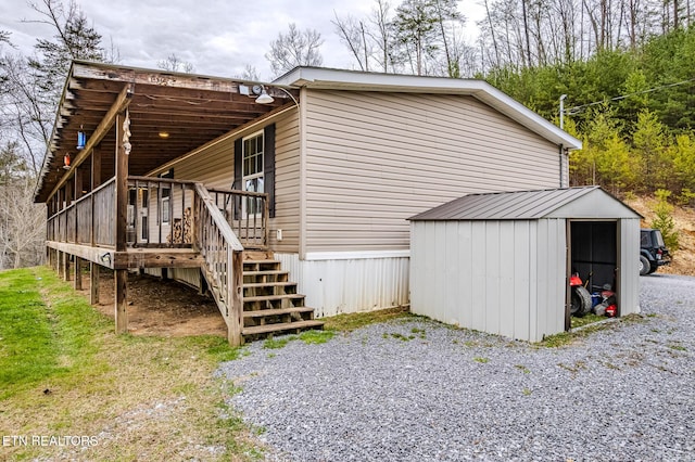 view of property exterior featuring a shed, stairway, a wooden deck, and an outdoor structure