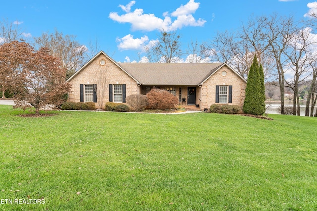 single story home with brick siding, a shingled roof, and a front yard