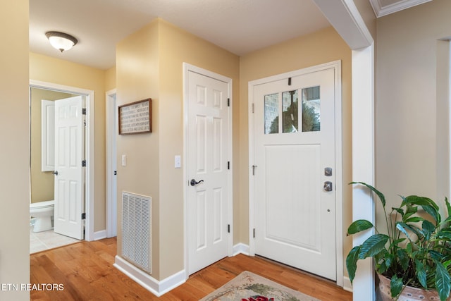 foyer entrance with light wood-type flooring, visible vents, and baseboards