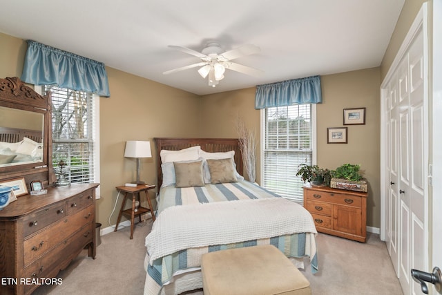 bedroom with a ceiling fan, light colored carpet, a closet, and baseboards