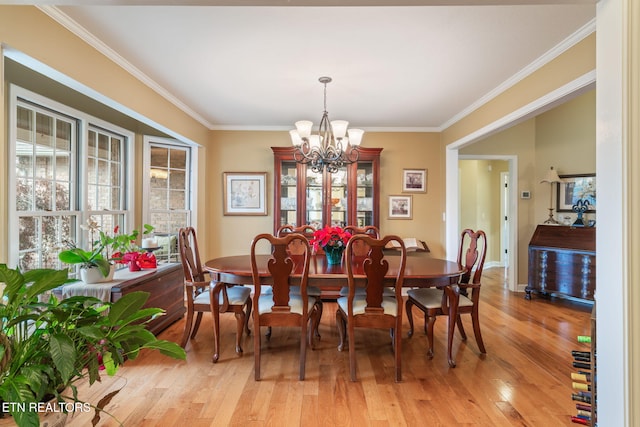 dining room with ornamental molding, light wood-style floors, baseboards, and a chandelier