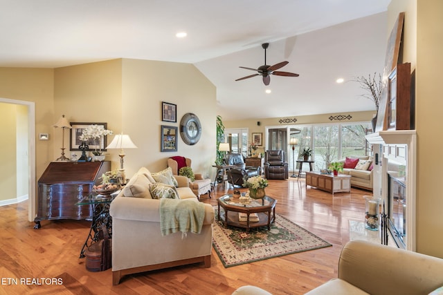 living area featuring vaulted ceiling, recessed lighting, a fireplace, and wood finished floors