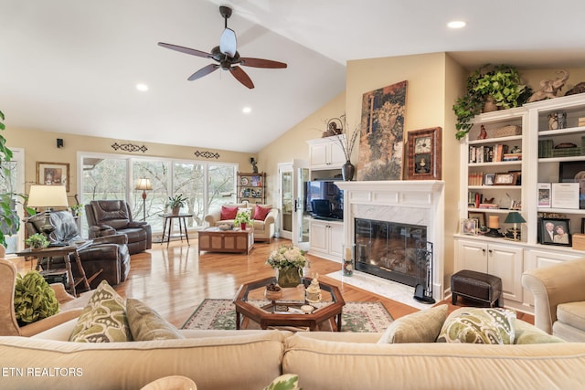 living area with a high end fireplace, light wood finished floors, lofted ceiling, recessed lighting, and a ceiling fan