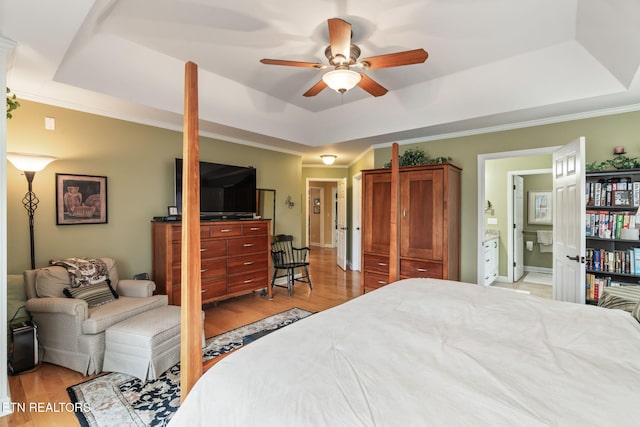 bedroom featuring a raised ceiling, crown molding, and light wood finished floors