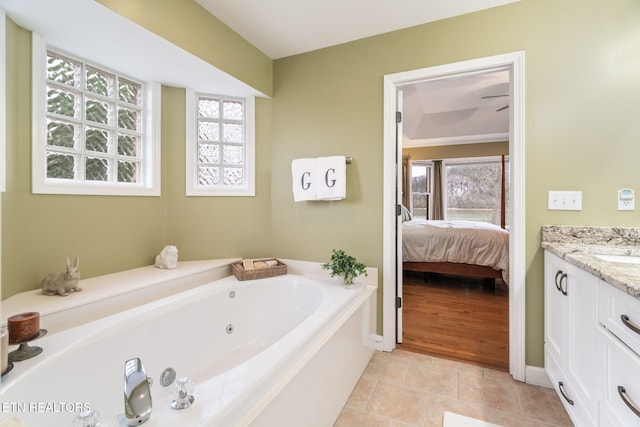 ensuite bathroom with vanity, ensuite bath, a healthy amount of sunlight, and a whirlpool tub