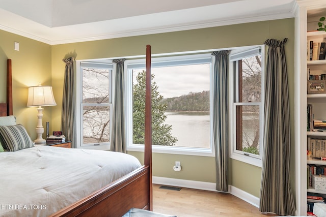 bedroom featuring visible vents, light wood-type flooring, baseboards, and ornamental molding