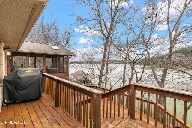 wooden deck with area for grilling, a water view, and a sunroom