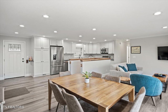 dining space with baseboards, recessed lighting, light wood-type flooring, and crown molding