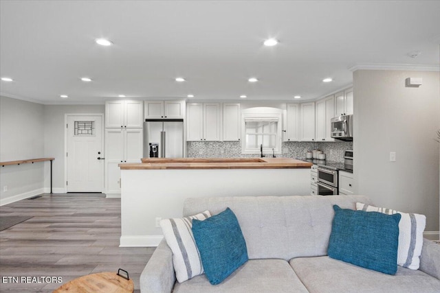 kitchen with appliances with stainless steel finishes, open floor plan, white cabinets, and backsplash