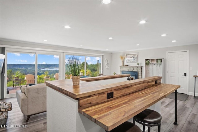 kitchen featuring ornamental molding, butcher block counters, a healthy amount of sunlight, and wood finished floors