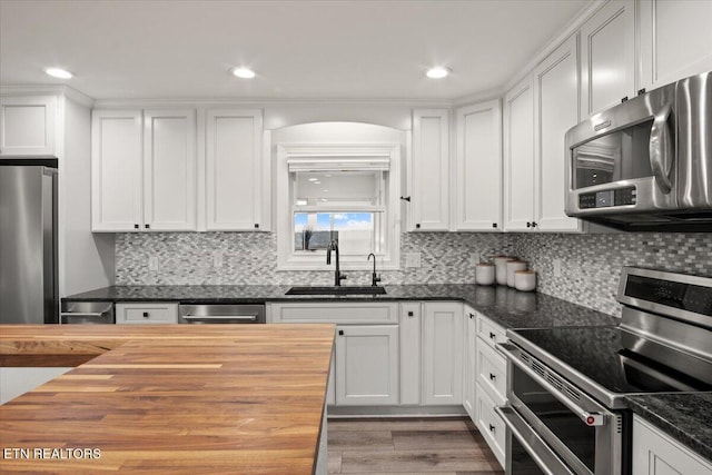 kitchen featuring appliances with stainless steel finishes, butcher block counters, and white cabinets