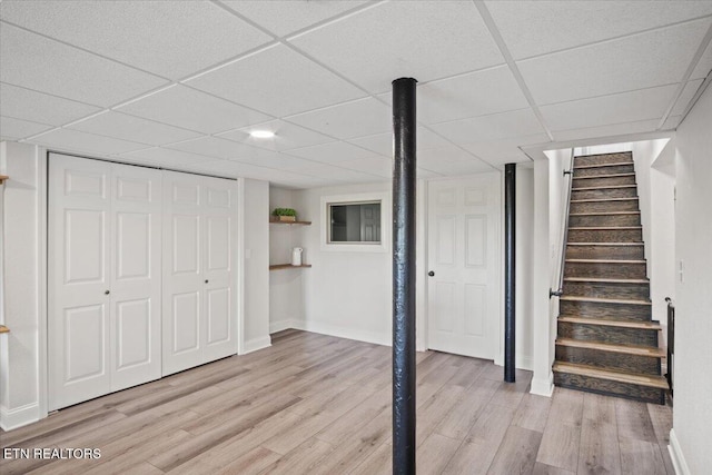 finished basement featuring light wood-style floors, stairway, and baseboards