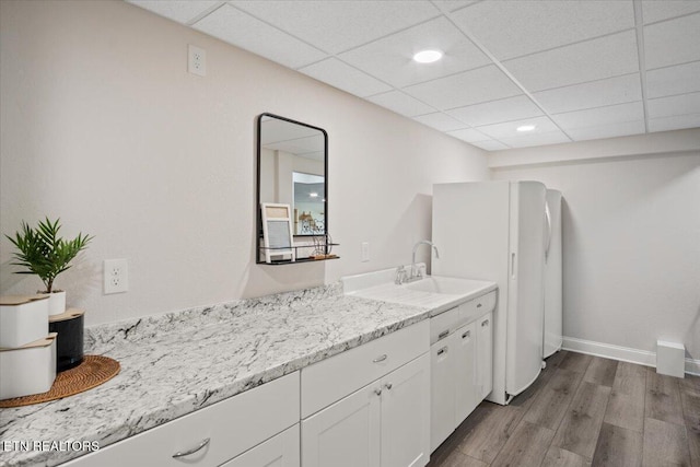 bathroom with a drop ceiling, wood finished floors, vanity, and baseboards