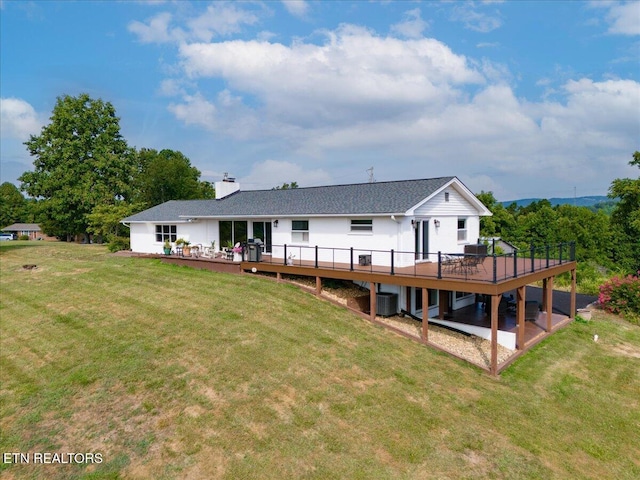 back of house with a chimney, a deck, and a yard