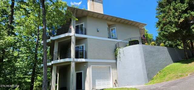 411 Maggie Mack Ln, Sevierville, TN 37862 - view of property exterior with a balcony, stucco siding, a chimney, and a garage