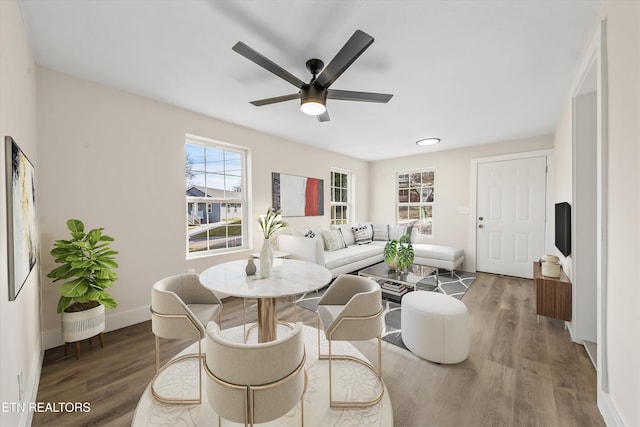 living area featuring a ceiling fan, baseboards, and wood finished floors