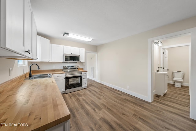 kitchen featuring white cabinetry, butcher block countertops, appliances with stainless steel finishes, and a sink