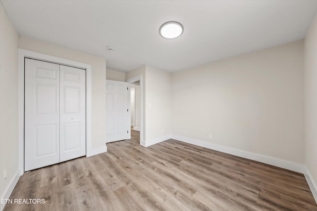 unfurnished bedroom featuring a closet, baseboards, and wood finished floors