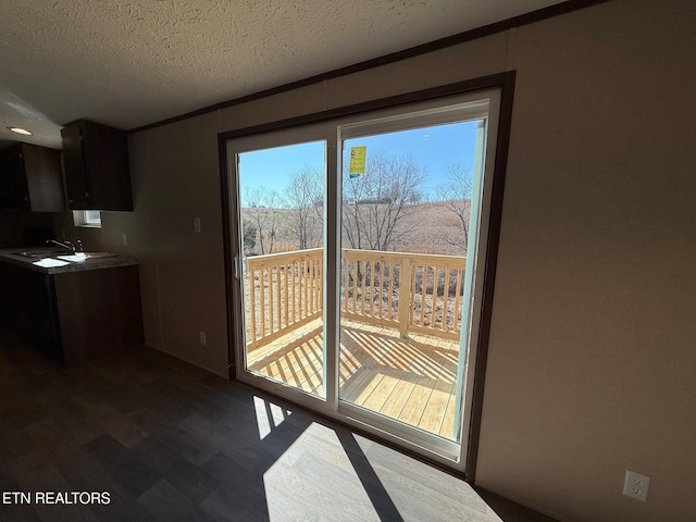 doorway to outside with dark wood-style floors and a textured ceiling