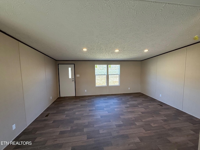 empty room featuring a textured ceiling and dark wood finished floors