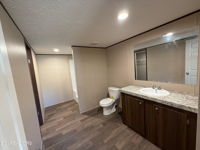 full bath with a textured ceiling, toilet, recessed lighting, wood finished floors, and vanity