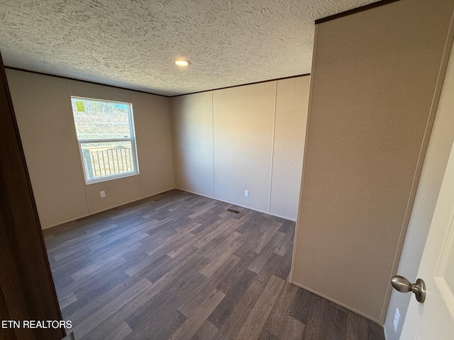 interior space with a textured ceiling, visible vents, and dark wood-type flooring