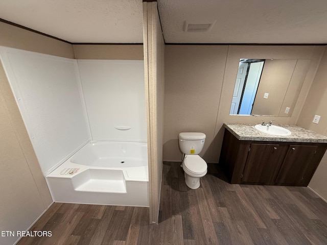 bathroom with a textured ceiling, vanity, toilet, and wood finished floors