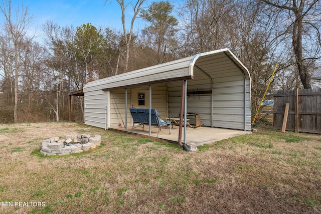 view of outbuilding with an outdoor fire pit and fence