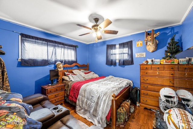 bedroom with a ceiling fan, ornamental molding, and dark wood-type flooring