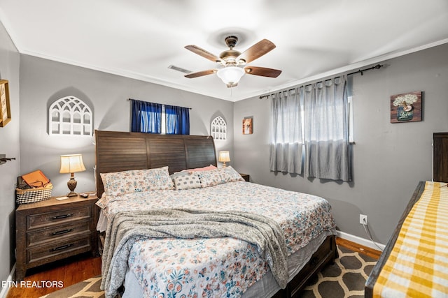 bedroom with crown molding, dark wood finished floors, visible vents, and baseboards