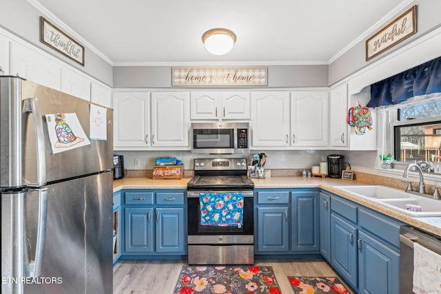 kitchen featuring appliances with stainless steel finishes, ornamental molding, blue cabinets, light countertops, and a sink