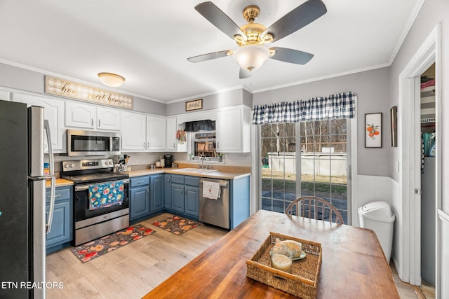 kitchen with white cabinets, blue cabinetry, stainless steel appliances, and a sink