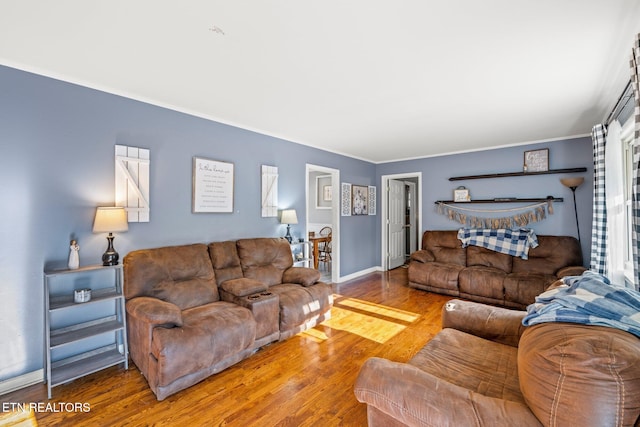 living area with baseboards, wood finished floors, and ornamental molding