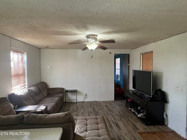 living area with ceiling fan, dark wood-type flooring, and a textured ceiling