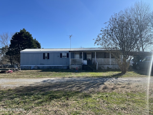 view of front of house with dirt driveway, metal roof, and a carport