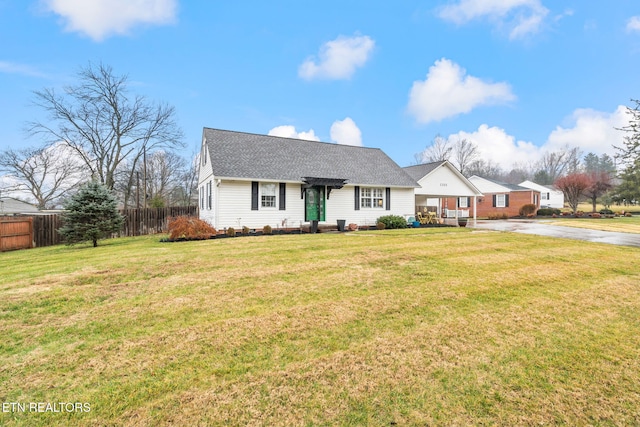 view of front of house with fence, a shingled roof, a front lawn, and concrete driveway