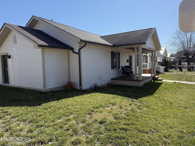 view of side of property featuring a porch, roof with shingles, and a yard