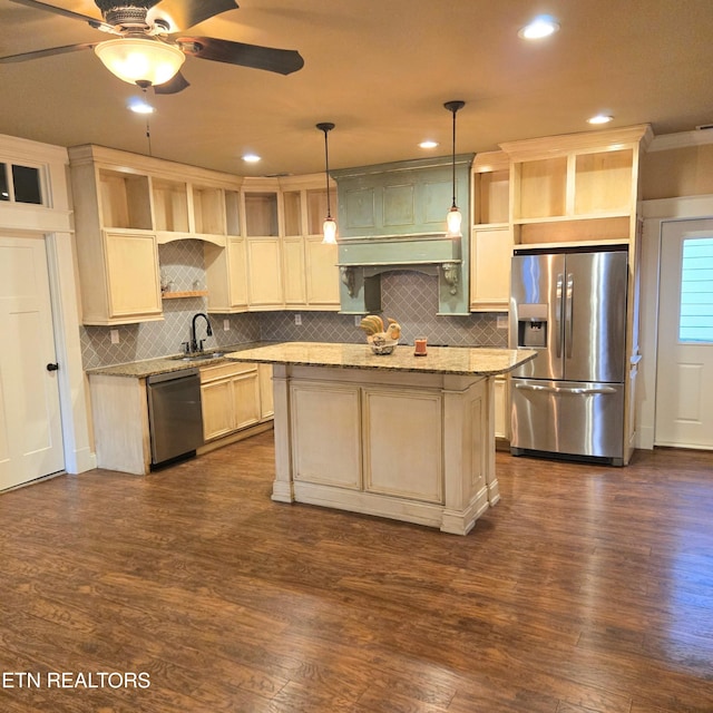 kitchen with appliances with stainless steel finishes, a center island, hanging light fixtures, and light stone countertops