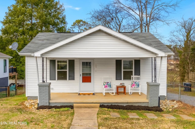 bungalow-style home featuring a porch, a shingled roof, and fence