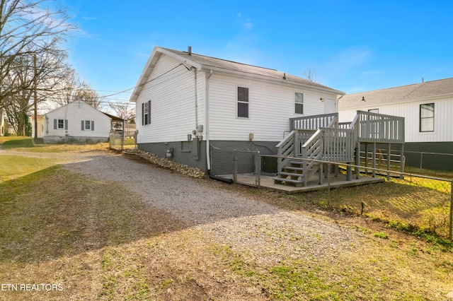 rear view of house with driveway, stairway, a wooden deck, and fence