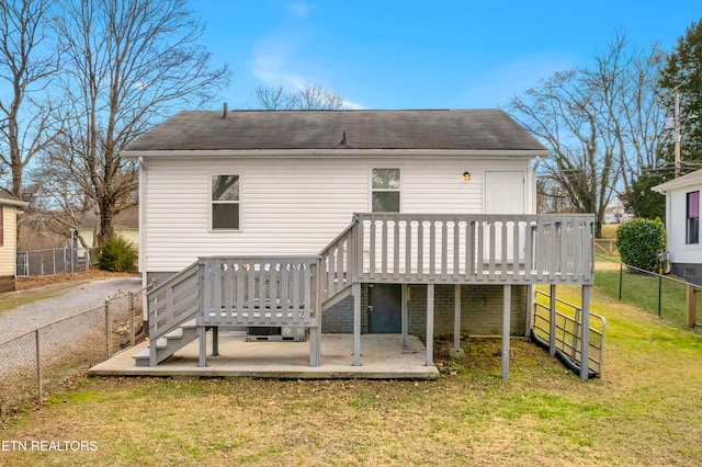 rear view of house featuring a deck, a yard, and a fenced backyard