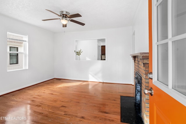 unfurnished living room featuring ceiling fan, a textured ceiling, wood finished floors, and baseboards